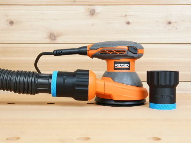 Black ToolCurve 1-7/8 inch hose adapter with blue band joining a vacuum hose to a Ridgid 5 in. sander, second adapter beside it