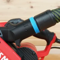 Hose adapter with blue band attached to Craftsman belt sander dust port, mounted on red power tool