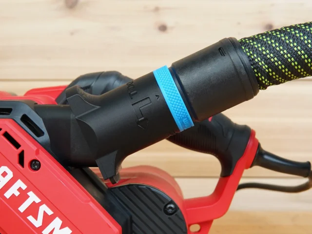 Hose adapter with blue band attached to Craftsman belt sander dust port, mounted on red power tool