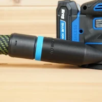Black hose adapter with blue band attached to a blue and black Kreg random orbit sander, connected to a yellow and black braided hose