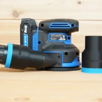 Black ToolCurve 1-7/8 inch hose adapter with blue band connected to a Kreg random orbit sander, second adapter beside it
