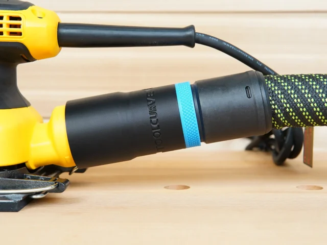 Black hose adapter with blue band attached to DeWalt yellow palm sander, connected to green braided hose