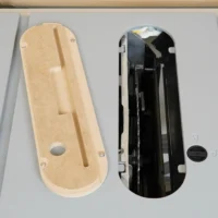 Tan MDF insert and black factory insert side by side, both showing top view with mounting holes and center slots for Kobalt 10" table saw