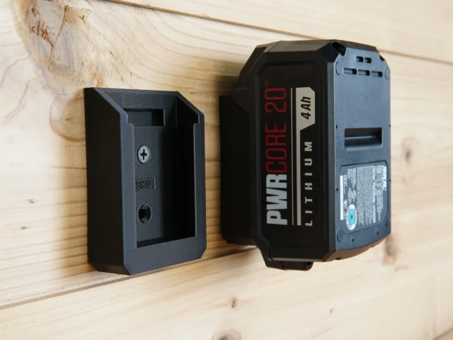 Black 3D-printed battery mount holder for SKIL 20v PWRCORE attached to wooden wall surface, with PWRCORE battery inserted into the mount