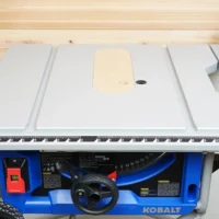 Zero clearance insert installed on Kobalt 10-inch table saw, showing beige MDF top surface with center opening and offset adjustment screw