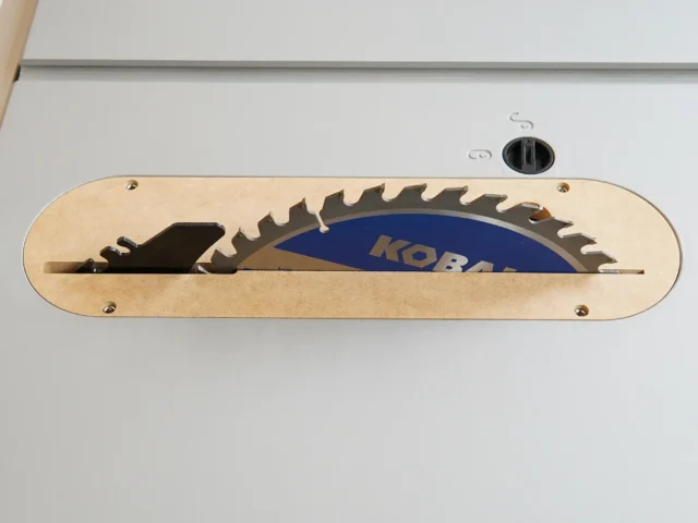 Light wood zero clearance insert with slot for saw blade, mounted on Kobalt 10" table saw with blue blade visible