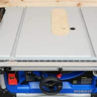 Natural wood zero clearance insert installed on Kobalt 10" table saw, with mounting holes and adjustment screw visible