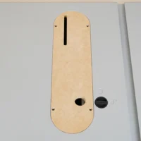 Tan MDF zero clearance insert for Kobalt 10″ table saw, top view showing vertical slot, oval opening, and mounting holes