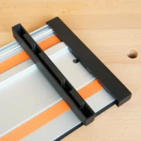 Black PETG protective caps fitted over each end of a Wen guide rail with orange and white straps, shown on a wooden surface