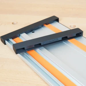 Two black ToolCurve end caps slid onto a Wen aluminum guide rail with orange strips, on a workbench