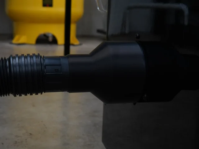 Black hose adapter with threaded 4-inch port on left end, connected to SawStop table saw dust collection port