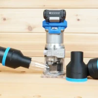 Black 2-1/2 inch hose adapter with blue ring on a vacuum hose beside a Kreg 20v trim router and a second adapter