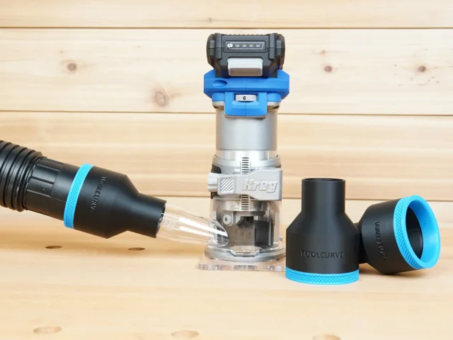 Black 2-1/2 inch hose adapter with blue ring on a vacuum hose beside a Kreg 20v trim router and a second adapter