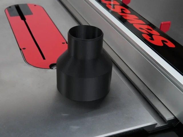 Black tapered hose adapter standing on a table saw, positioned near the rear dust port area next to a red track rail