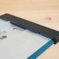Black protective cap slid onto the end of a blue Bosch guide rail, shown on a wooden surface
