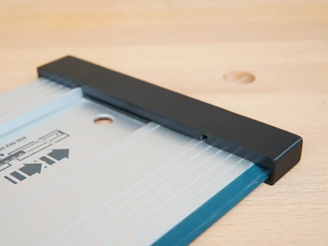 Black protective cap slid onto the end of a blue Bosch guide rail, shown on a wooden surface