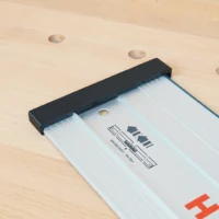 Black PETG protective cap installed on the end of a Bosch guide rail, showing the friction fit grip over the aluminum profile