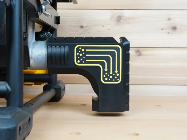 Black plastic bucket adapter with yellow-outlined dust routing diagram, mounted on rear port of DeWalt table saw