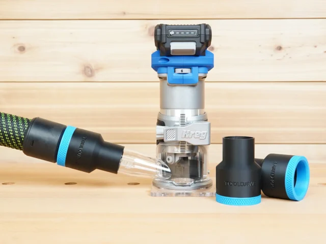 Black 36mm hose adapter with blue trim on a vacuum hose beside a Kreg 20v trim router and two spare adapters