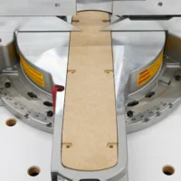 Natural wood zero clearance insert centered between two angle gauges on a Dewalt miter saw, shown from above