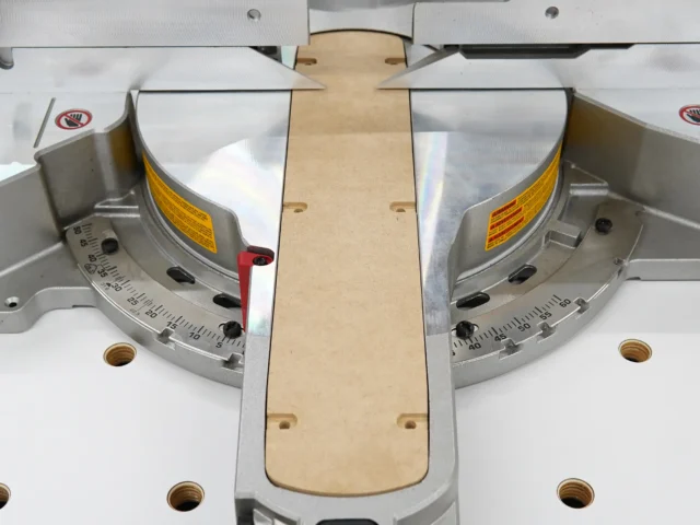 Natural wood zero clearance insert centered between two angle gauges on a Dewalt miter saw, shown from above