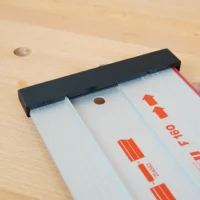 Black protective cap installed on the end of a Mafell guide rail with red branding visible on the white aluminum rail