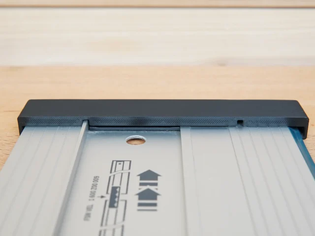 Black protective cap sliding onto end of Bosch aluminum guide rail, showing friction fit design