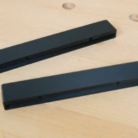 Two black protective caps for Mafell guide rails, shown separately on wood surface