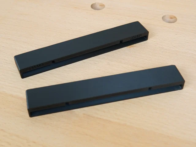 Two black protective caps for Mafell guide rails, shown separately on wood surface