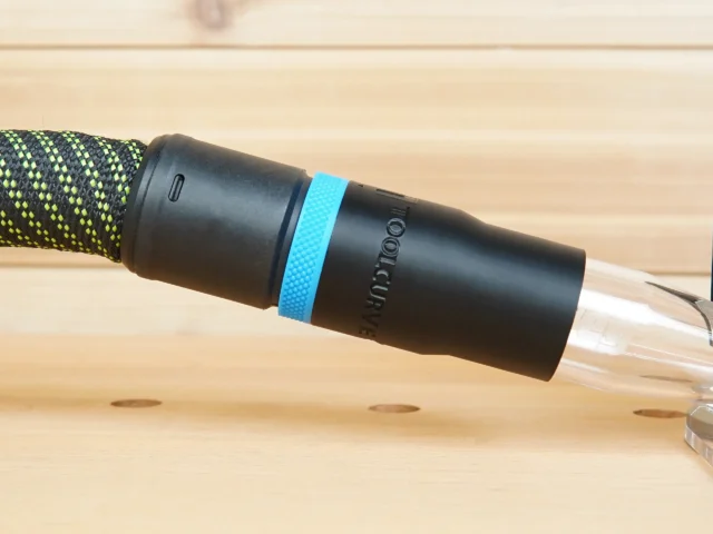 Black hose adapter with blue band attached to Kreg 20v trim router, connected to braided hose