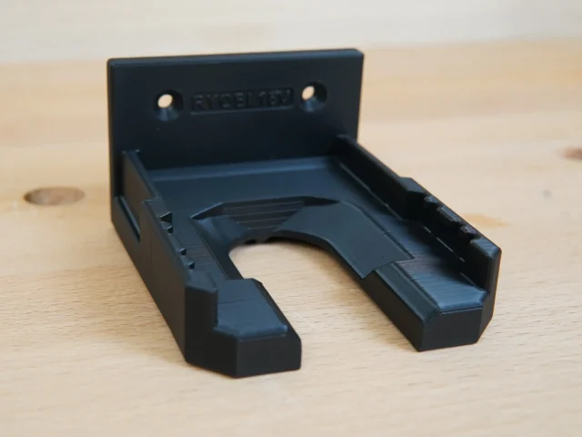 Black wall-mount battery holder for Ryobi 18v battery, shown from above with mounting holes visible