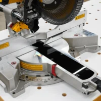 Black zero clearance insert fitted into the throat plate of a Dewalt 12-inch sliding miter saw on a white bench