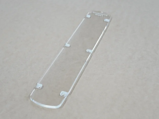 Clear acrylic zero clearance insert for DeWalt 12" miter saw, shown from above with mounting tabs visible along edges