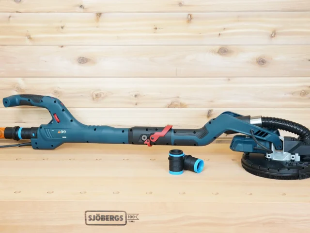 Two black 1-1/4 inch hose adapters with blue rings resting beside a Bosch 9in drywall sander on a bench