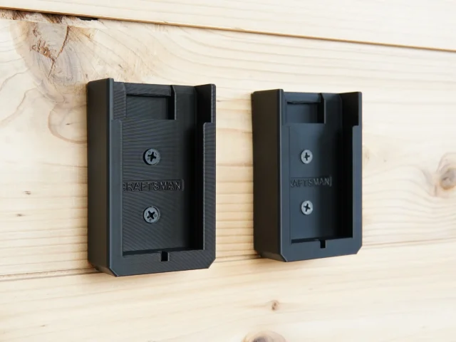 Two black Craftsman 20v battery mounts mounted on light wood, each with two Phillips screws visible and a slot for battery insertion