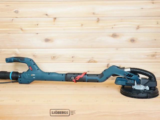 Bosch 9in drywall sander lying on a workbench, its dust port joined to a shop vac hose by the 2-1/2 inch adapter