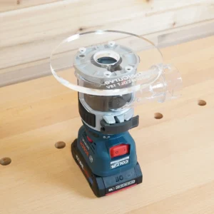 Clear 6-inch round acrylic router base plate mounted on an upside-down Bosch Colt 18V trim router