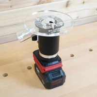Clear 6-inch round acrylic router base plate mounted on an upside-down Skil 20V trim router on a bench