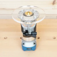 6-inch round clear acrylic router base plate mounted on a Hercules trim router, showing brass bushing and measurement scale