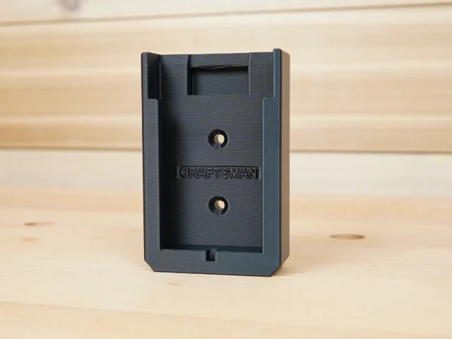 Black plastic Craftsman 20v battery mount with two mounting holes and internal clip slot, shown standing upright