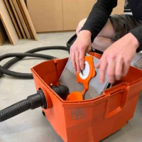 Macam reusable dust bag installed in orange FEIN Turbo dust extractor, showing gray filter material and orange internal components