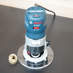 6-inch round clear acrylic router base plate mounted on a Bosch Colt 1.25 HP router, with a brass guide bushing adapter shown separately beside it