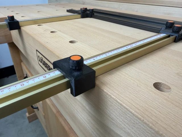 Black plastic parallel guide with orange knob mounted on brass Incra T-Track rail attached to Ridgid track saw guide rail