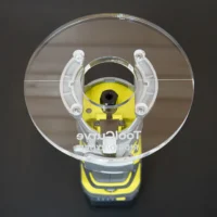 6 inch round clear acrylic base plate mounted on yellow Ryobi trim router, showing brass guide bushing and mounting hardware from above
