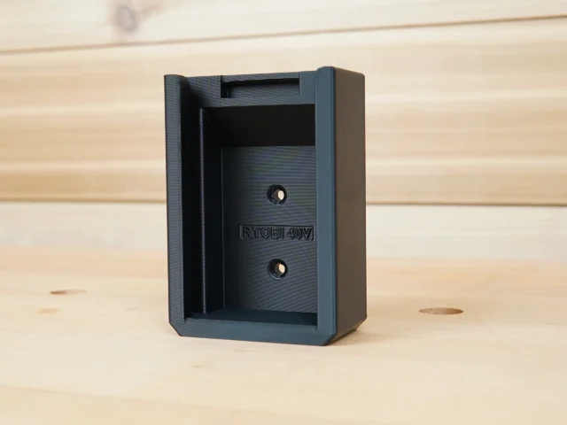 Black plastic battery holder mount for Ryobi 40v batteries, shown from front with two mounting holes and slot opening visible