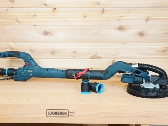 Two black and blue 1-7/8 inch hose adapters on a workbench beside a Bosch 9in drywall sander, one fitted to the vac hose