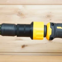 Yellow and black hose adapter connected between braided green hose and Dewalt drywall sander dust port
