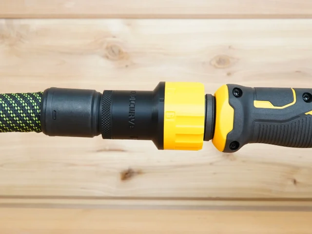 Yellow and black hose adapter connected between braided green hose and Dewalt drywall sander dust port