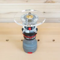 6-inch round clear acrylic router base plate mounted on a Porter Cable trim router, showing the brass center collet and guide bushing hole from above.