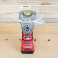 6-inch round clear acrylic base plate mounted on red Craftsman trim router, showing brass center insert and guide bushing port